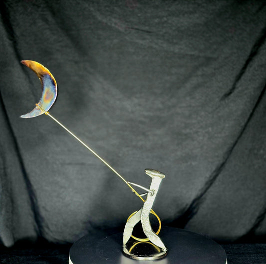 Left view, I Swear: By the Stars and the Moon Above mixed-media metal sculpture by Texas artist Enrique Del Angel, featuring a railroad spike cowboy roping a crescent moon filled with stars.