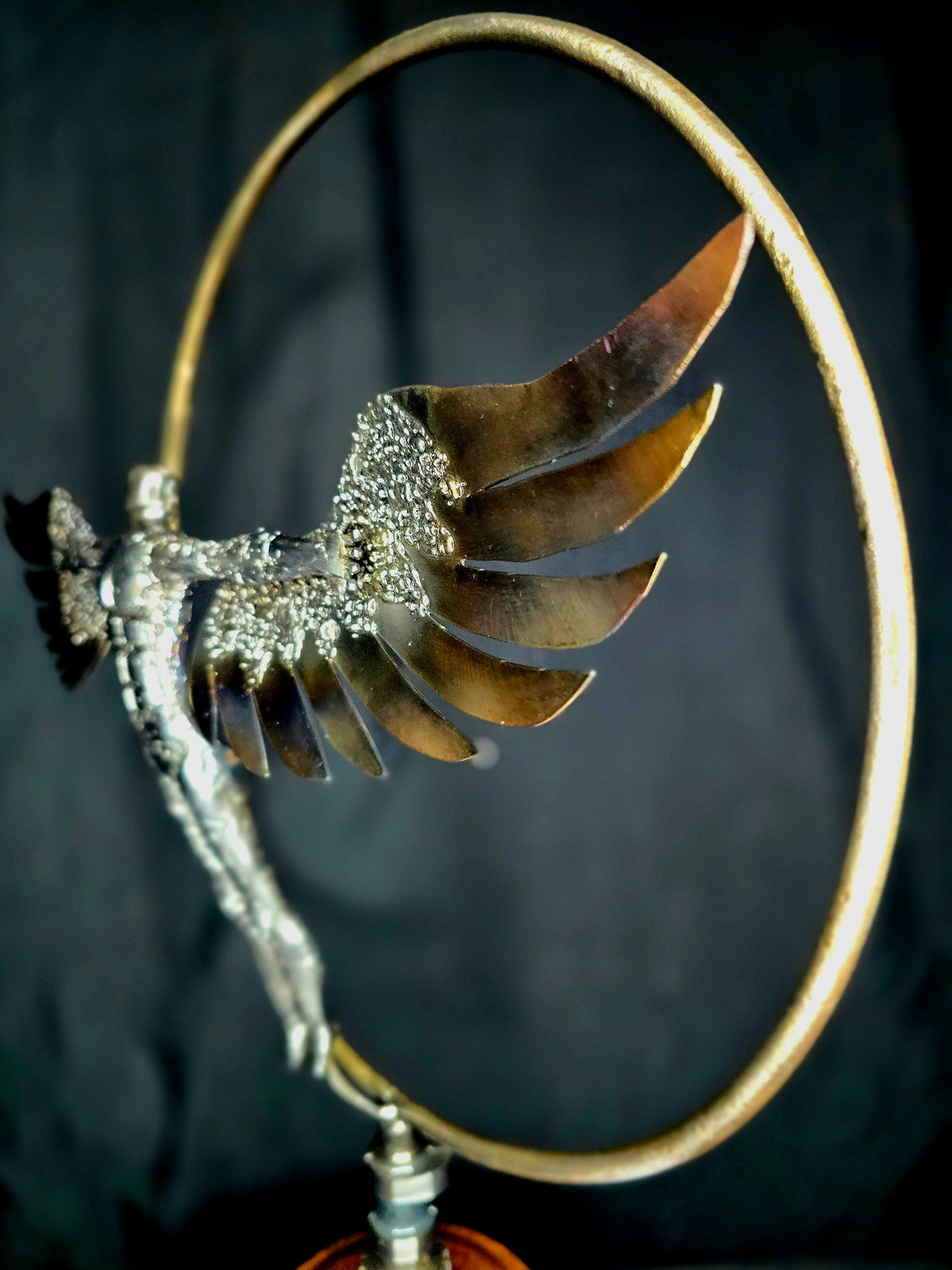 Ikarus: The Day After sculpture by Enrique Del Angel. Metal figure with wings in a golden circle.