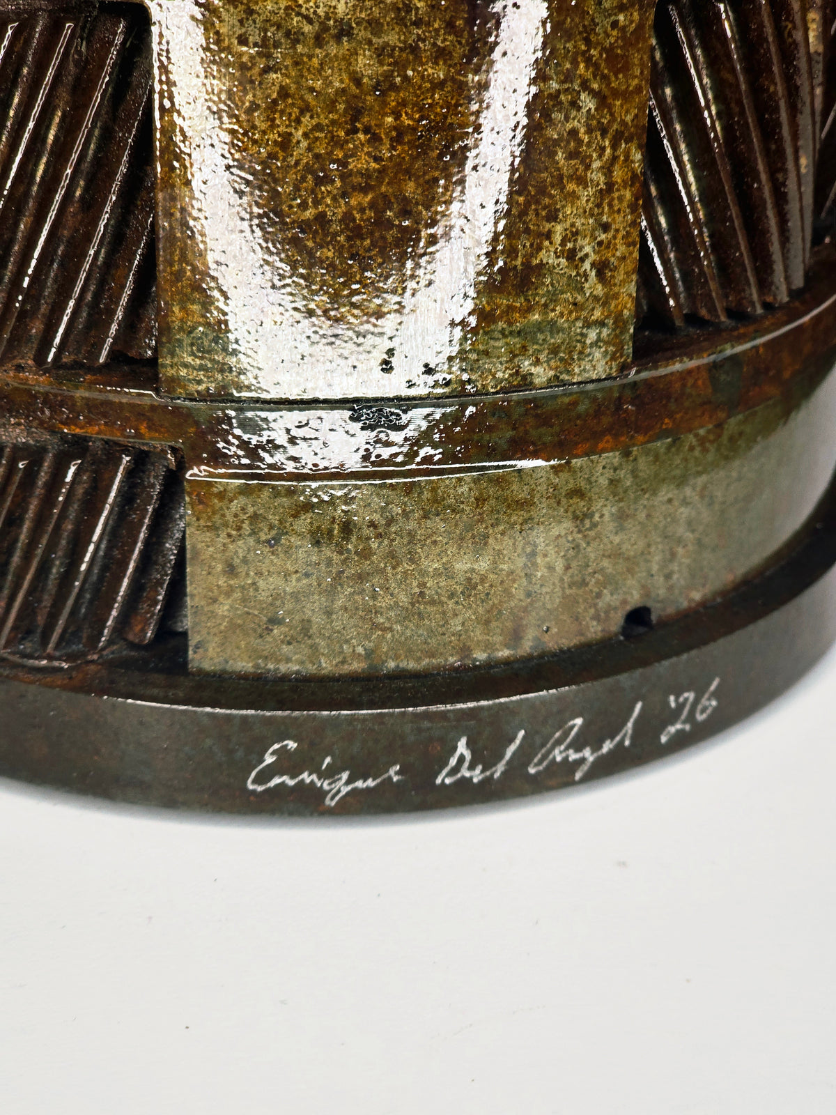 Ikarus: The Day After sculpture by Enrique Del Angel, 2026. Close-up of textured metal with inscribed signature.