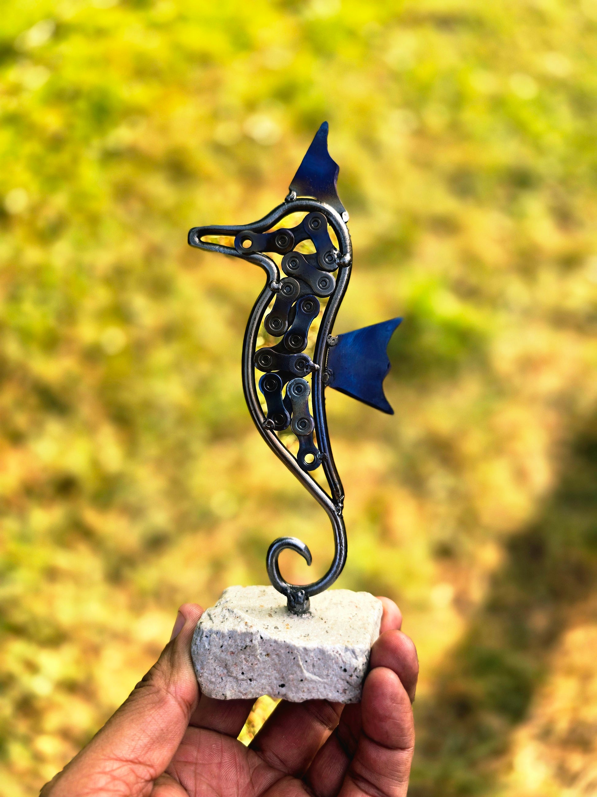 Metal seahorse sculpture with blue fins on stone base