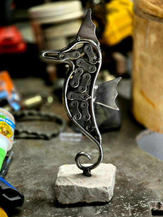Silver metal seahorse sculpture on stone base with curled tail