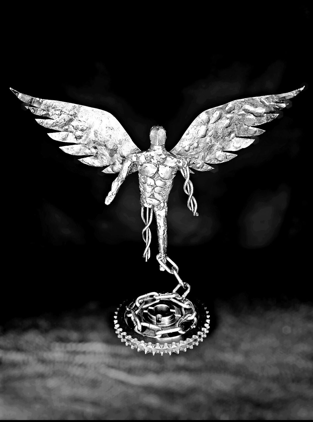 Black-and-silver metal angel ornament with wide wings and circular gear base
