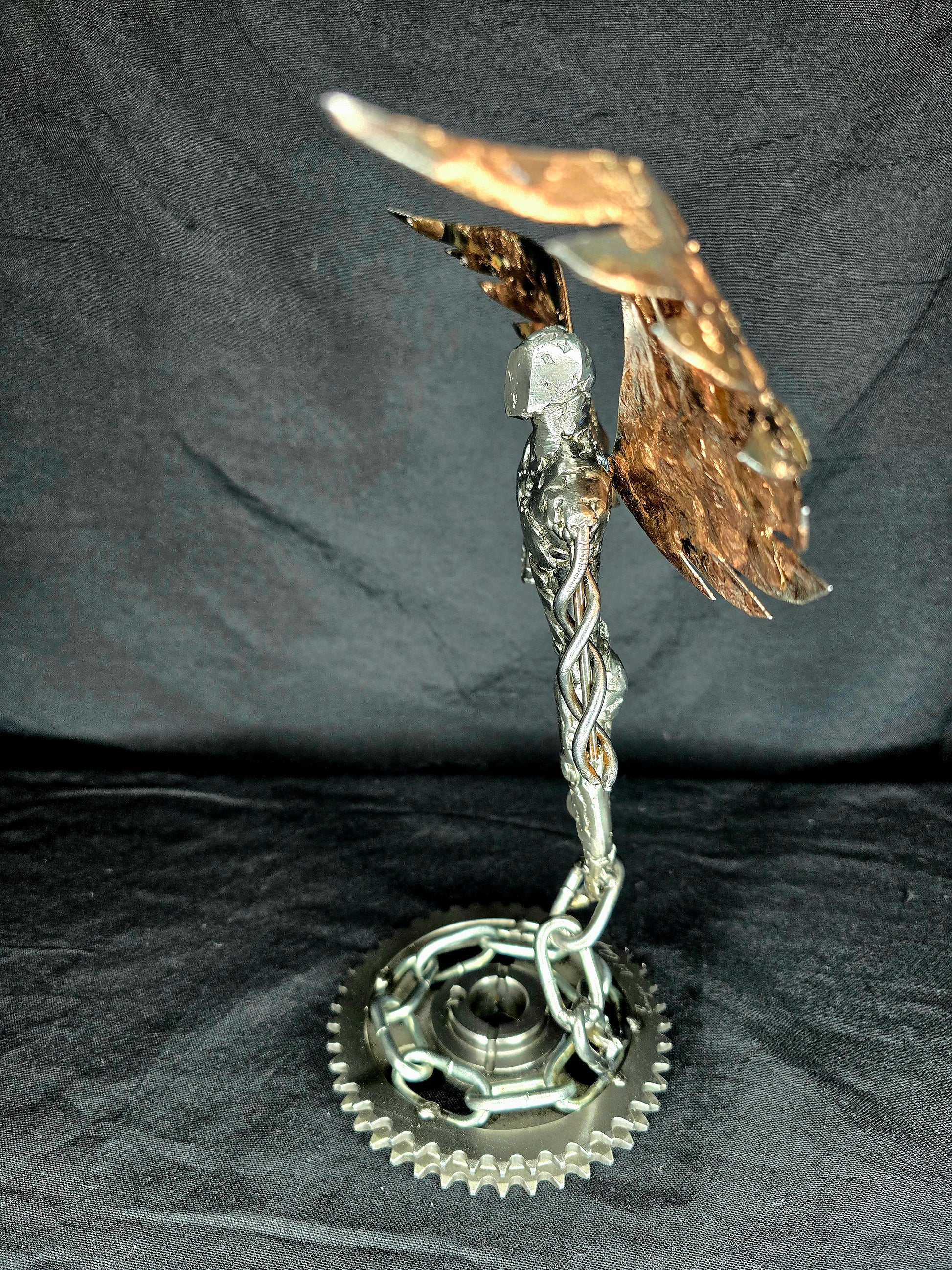 Metal angel ornament from the side with gold-toned wings and linked chain base
