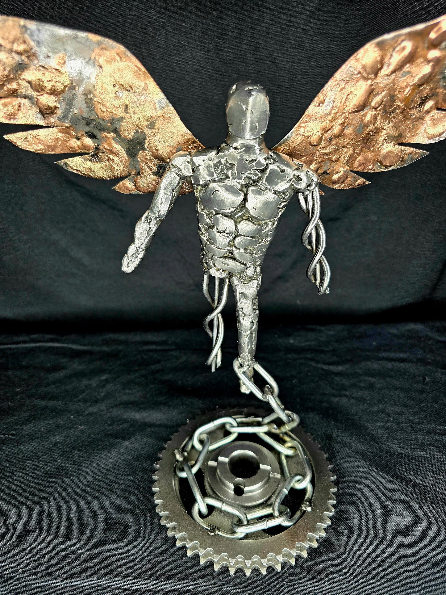 Metal angel ornament with gold wings, detailed silver torso, and round gear base