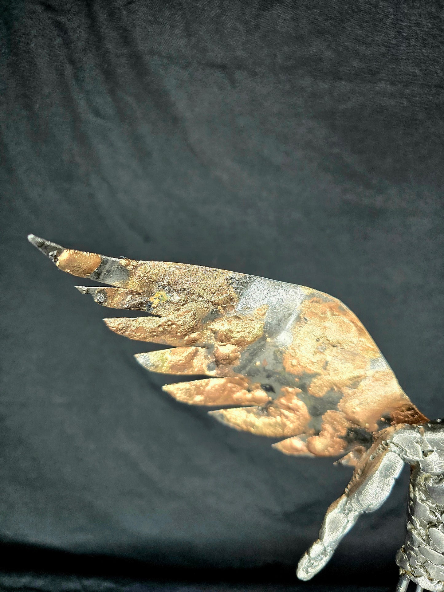 Metal angel ornament close-up of gold-toned wing and silver linked body