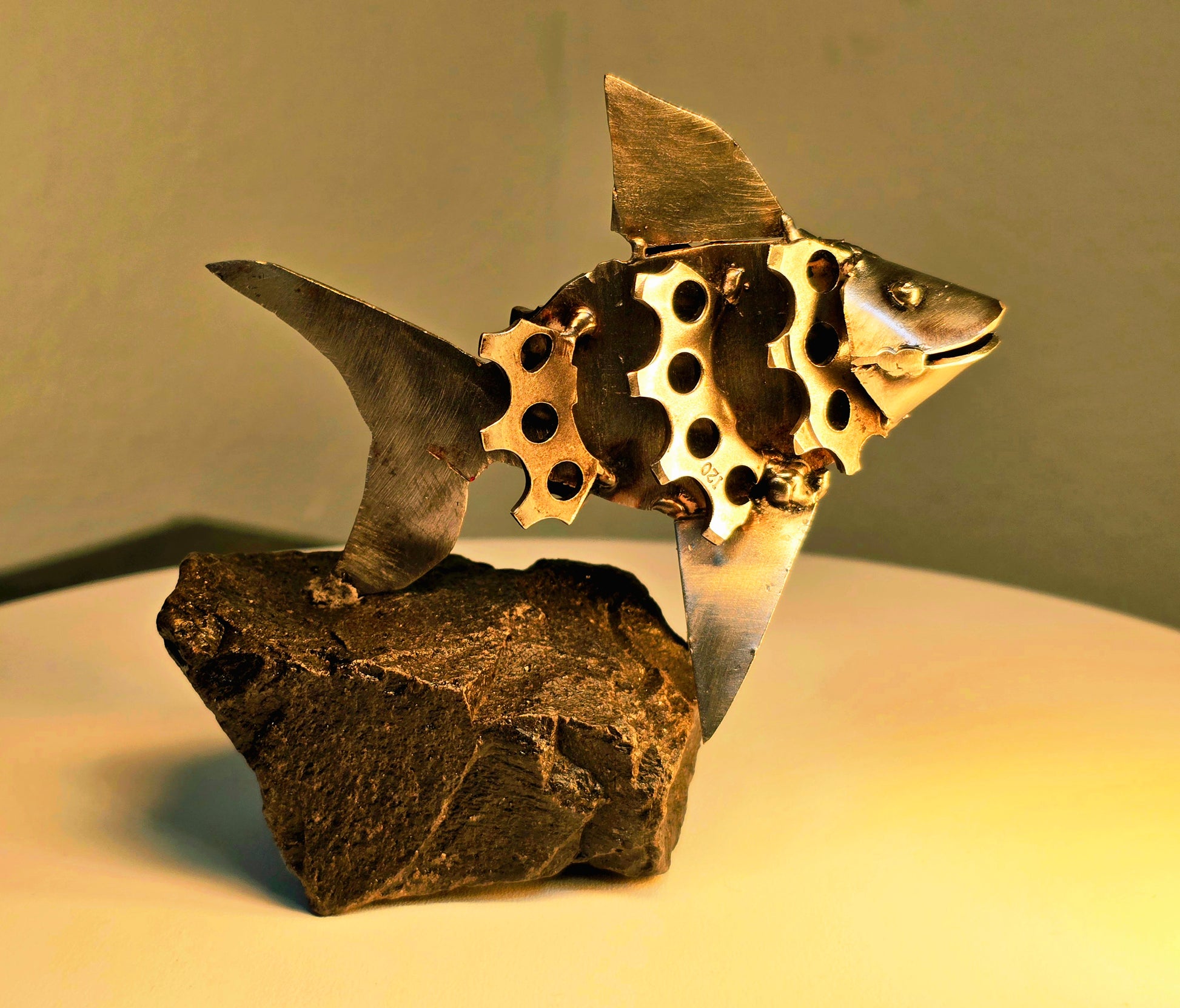 Barry the Goldfish welded steel fish sculpture by Enrique Del Angel handcrafted from upcycled bicycle gears on a stone base