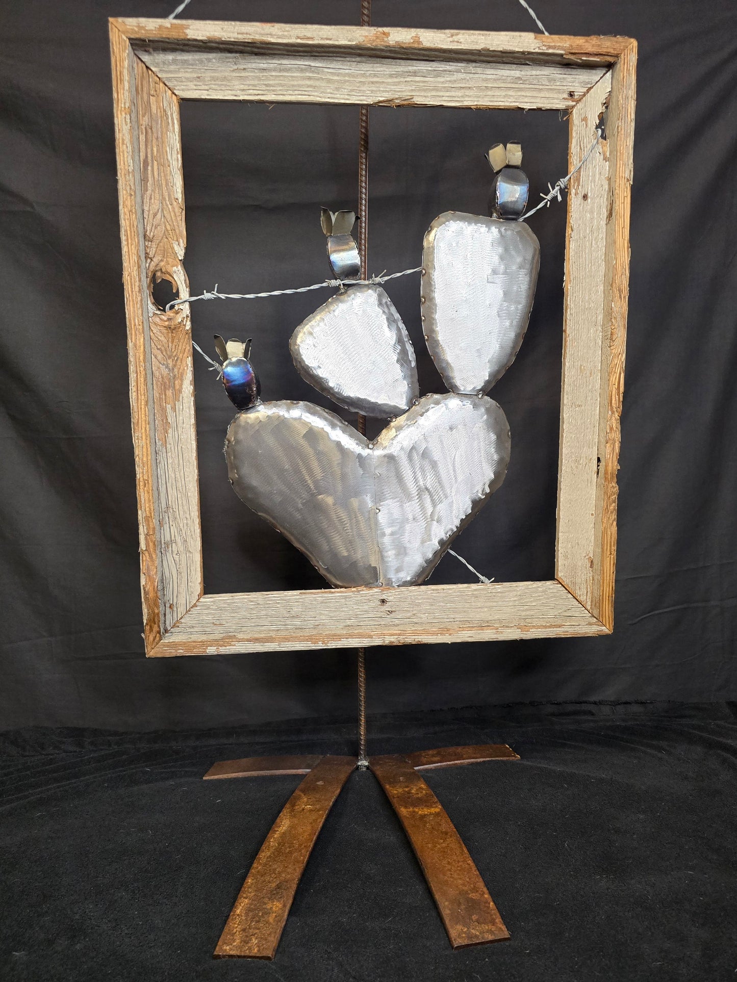 Symbolic cactus family metal sculpture with barbed wire and antique frame, reflecting love, hardship, and the strength of family by Enrique Del Angel.