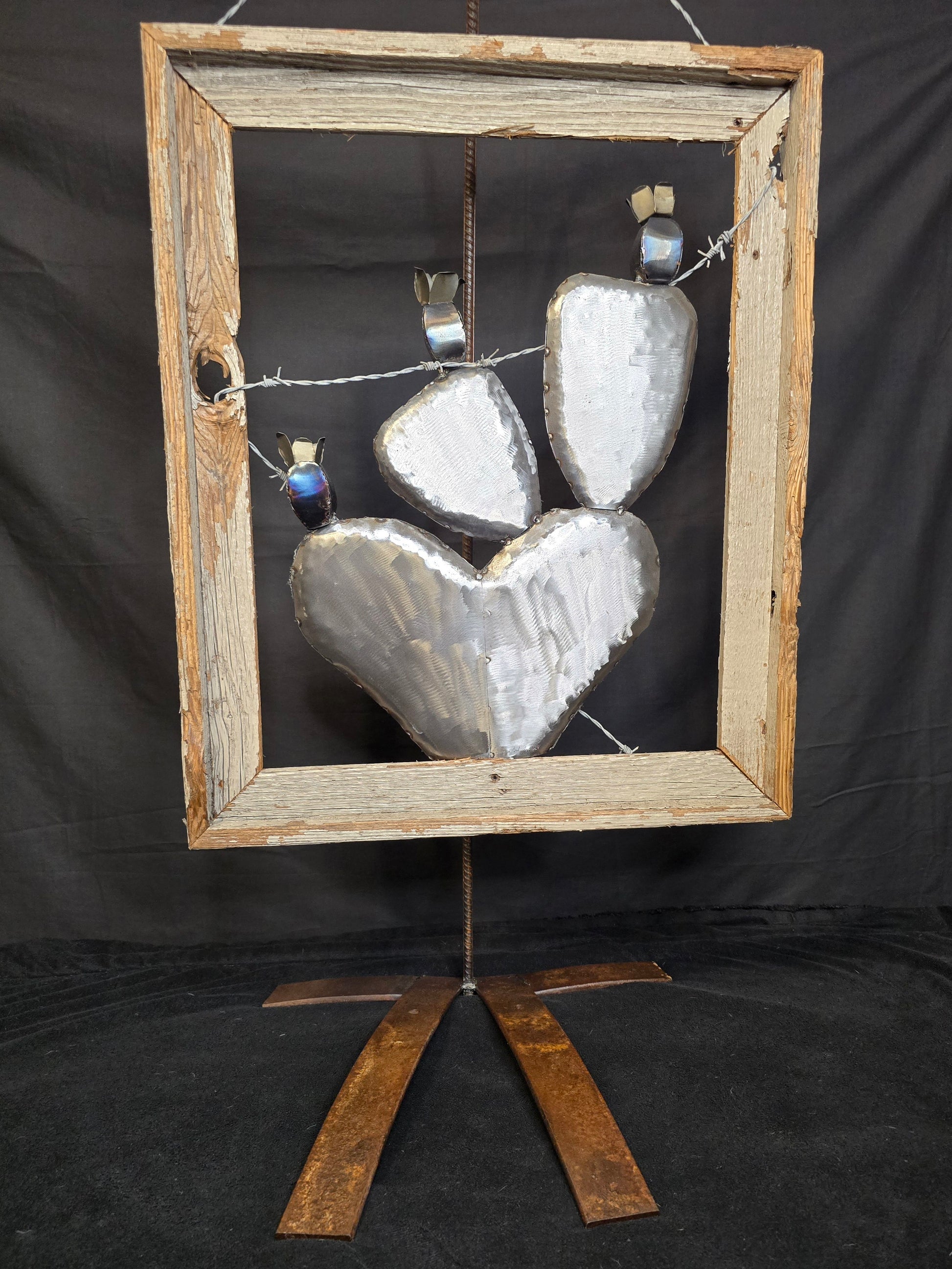 Symbolic cactus family metal sculpture with barbed wire and antique frame, reflecting love, hardship, and the strength of family by Enrique Del Angel.