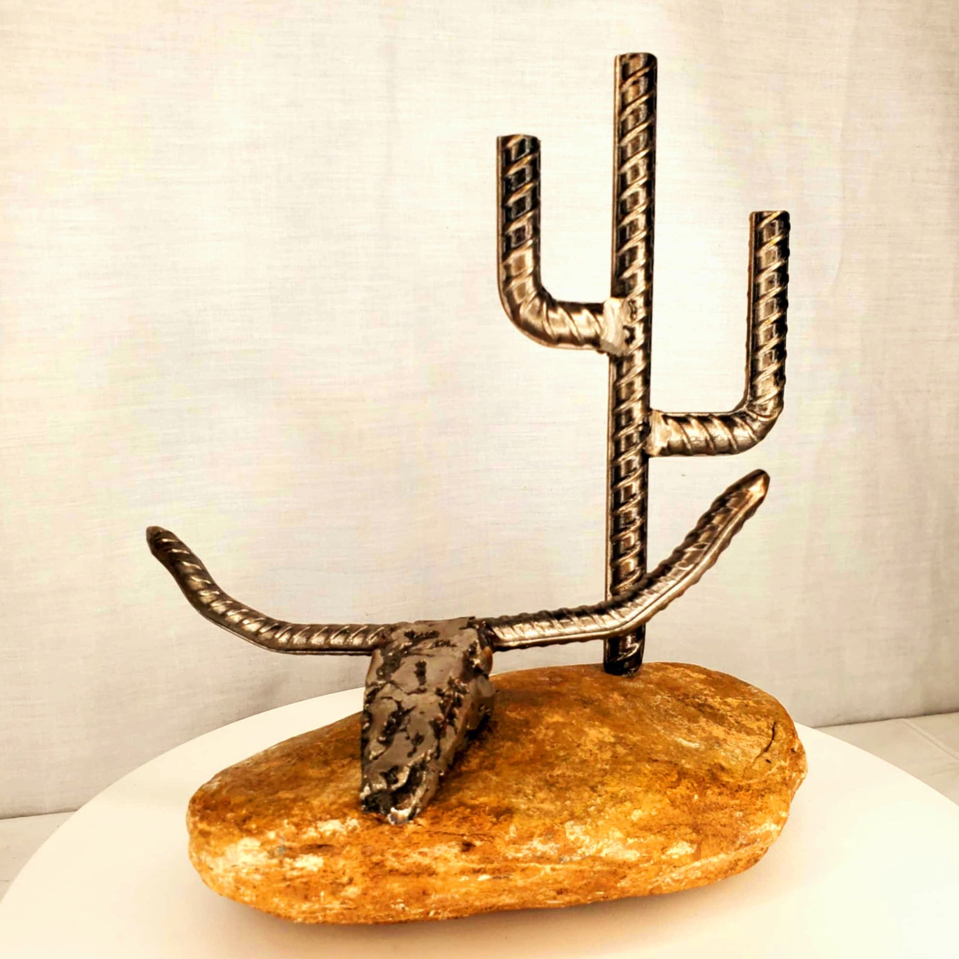 Desert inspired metal sculpture with longhorn skull, rocks, and saguaro cactus, forged from reclaimed steel by Enrique Del Angel.