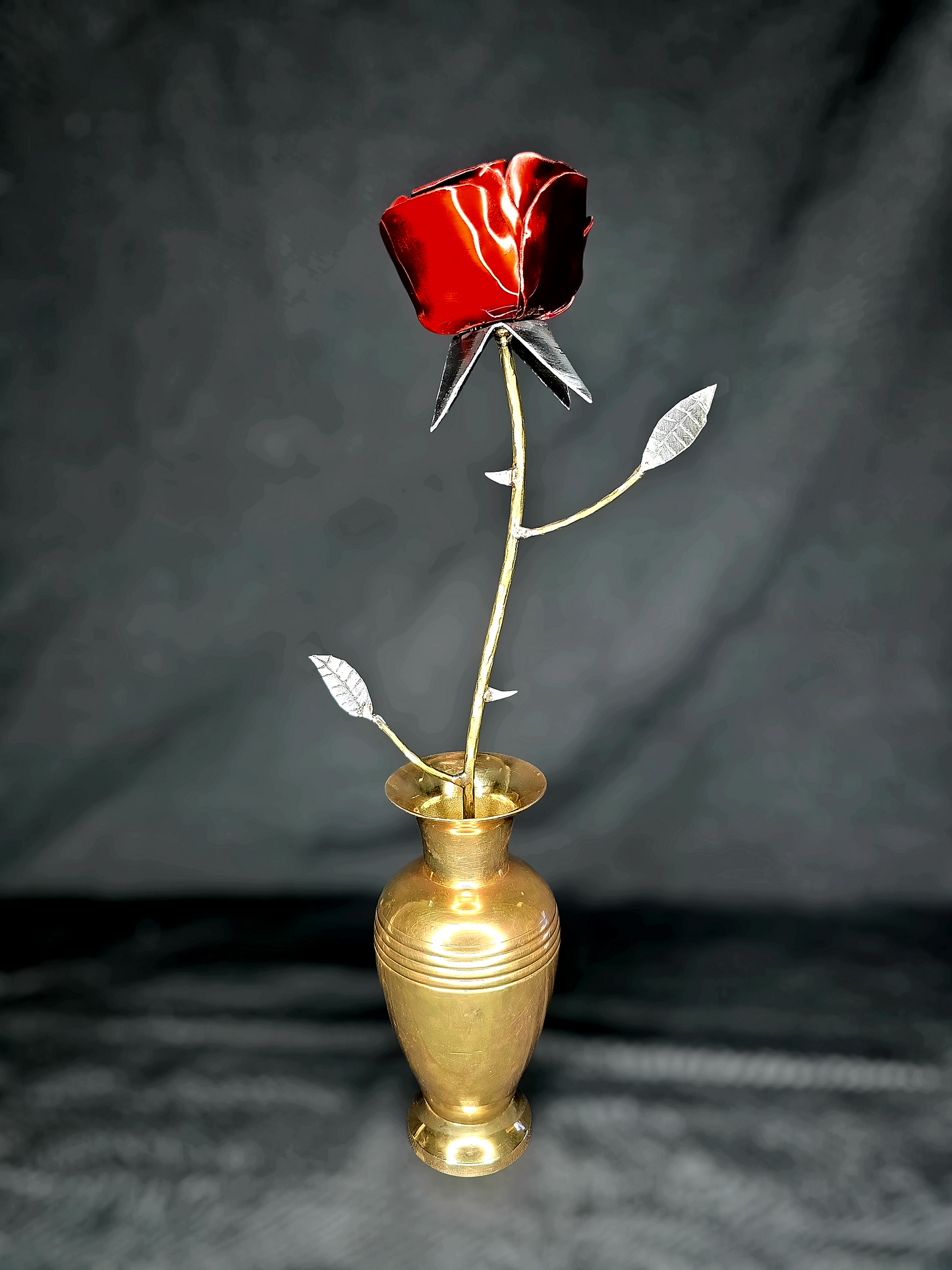 Handcrafted metal rose sculpture with thorns, symbolizing resilience and new life, made from reclaimed steel and brass by Enrique Del Angel.