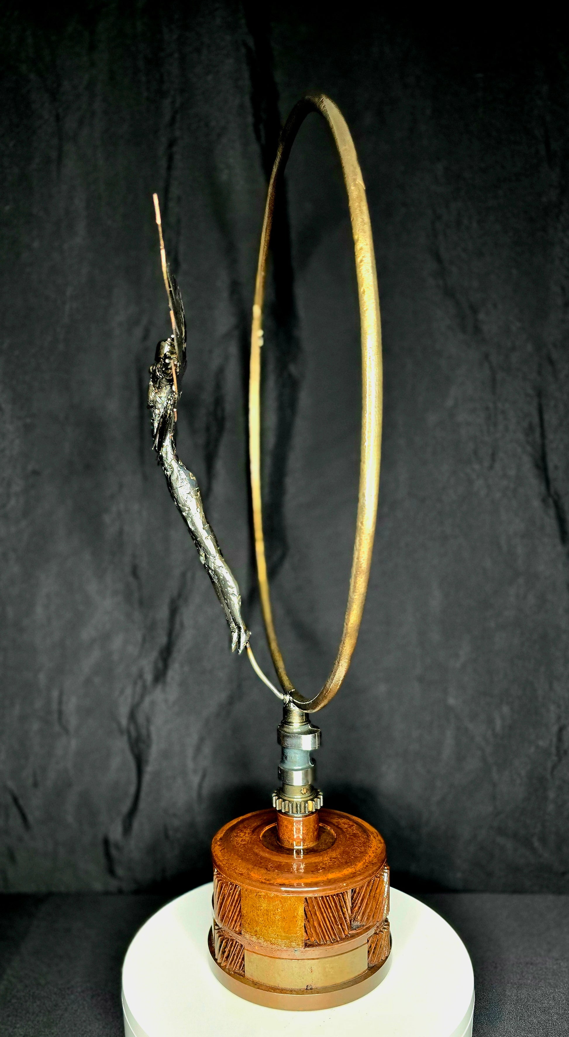 Ikarus: The Day After sculpture by Enrique Del Angel. A metal figure leaps towards a golden ring, mounted on a wooden base.