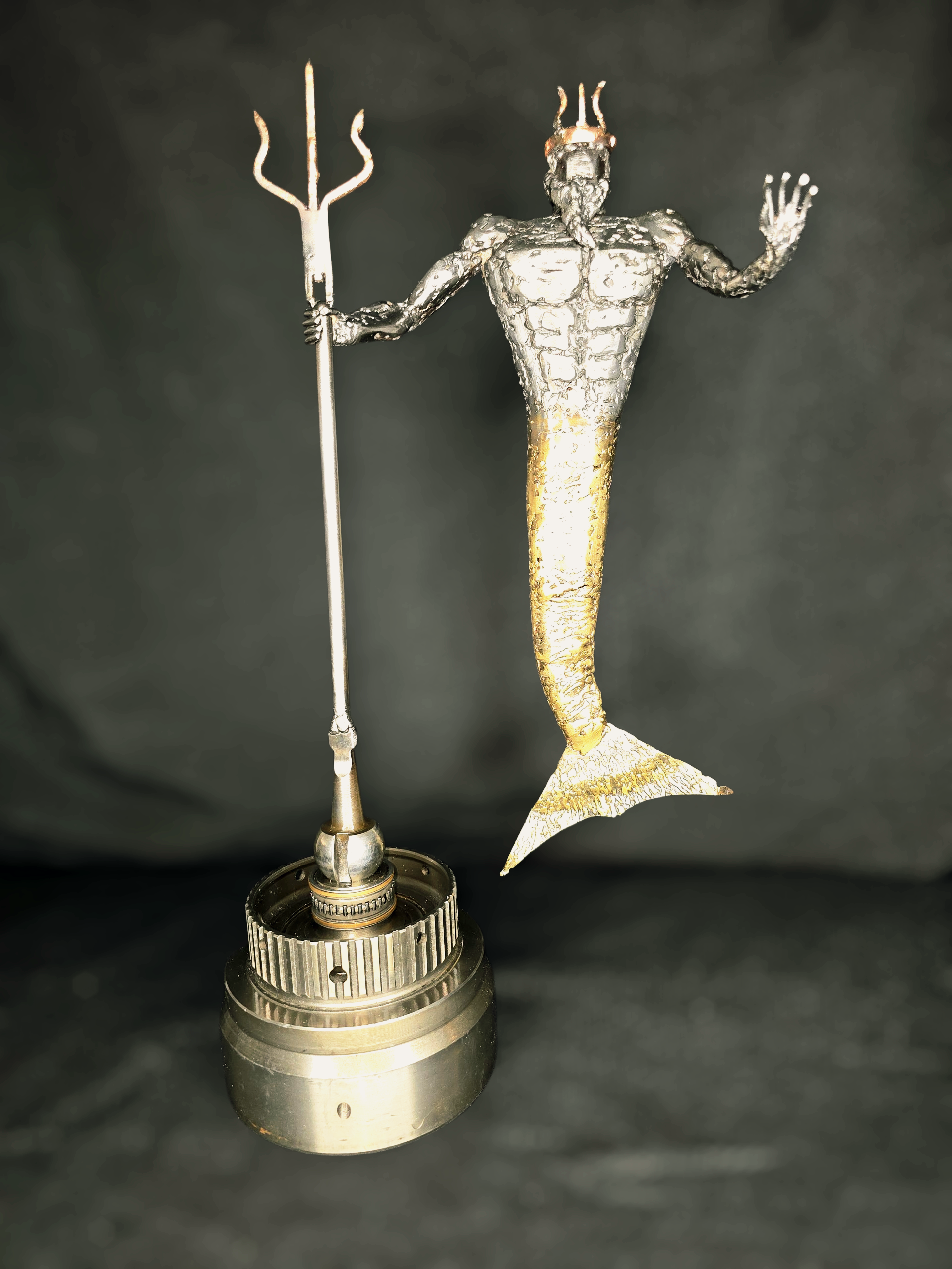 Handcrafted metal sculpture of Poseidon holding a trident, inspired by Greek mythology and forged from reclaimed automotive parts by Enrique Del Angel.