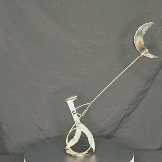 I Swear: By the Stars and the Moon Above mixed-media metal sculpture by Texas artist Enrique Del Angel, featuring a railroad spike cowboy roping a crescent moon filled with stars.