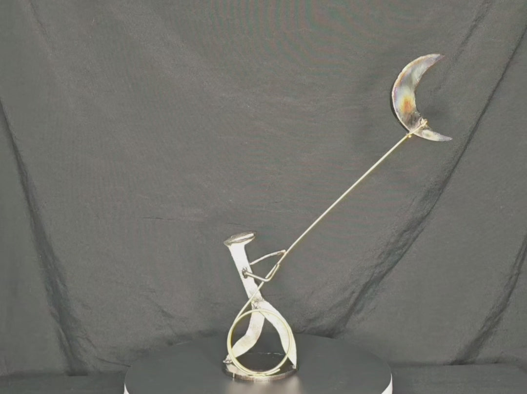 I Swear: By the Stars and the Moon Above mixed-media metal sculpture by Texas artist Enrique Del Angel, featuring a railroad spike cowboy roping a crescent moon filled with stars.