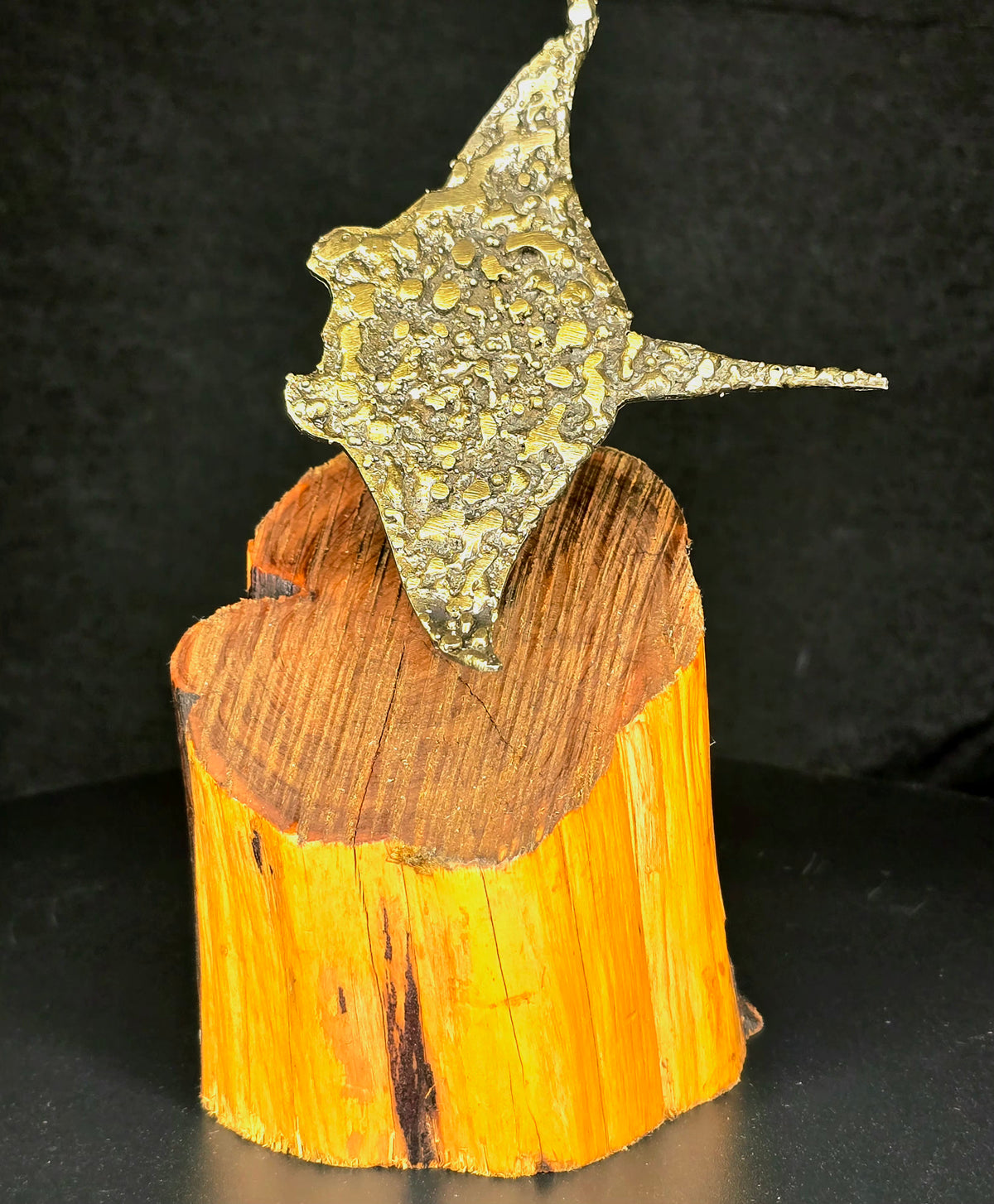 Brass plated hand-formed steel sculpture of three cownose rays mounted on a natural wood base.
