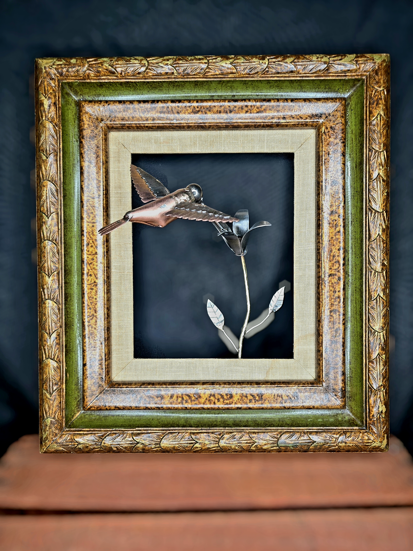Framed metal bird wall art with copper body, silver wings, and a metal flower in frame