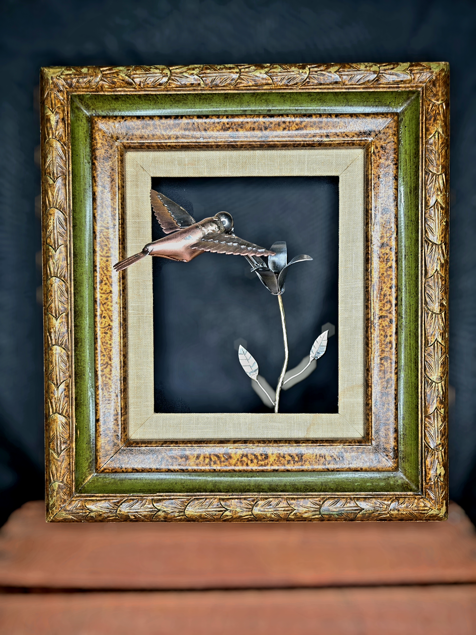 Framed metal bird wall art with copper body, silver wings, and a metal flower in frame