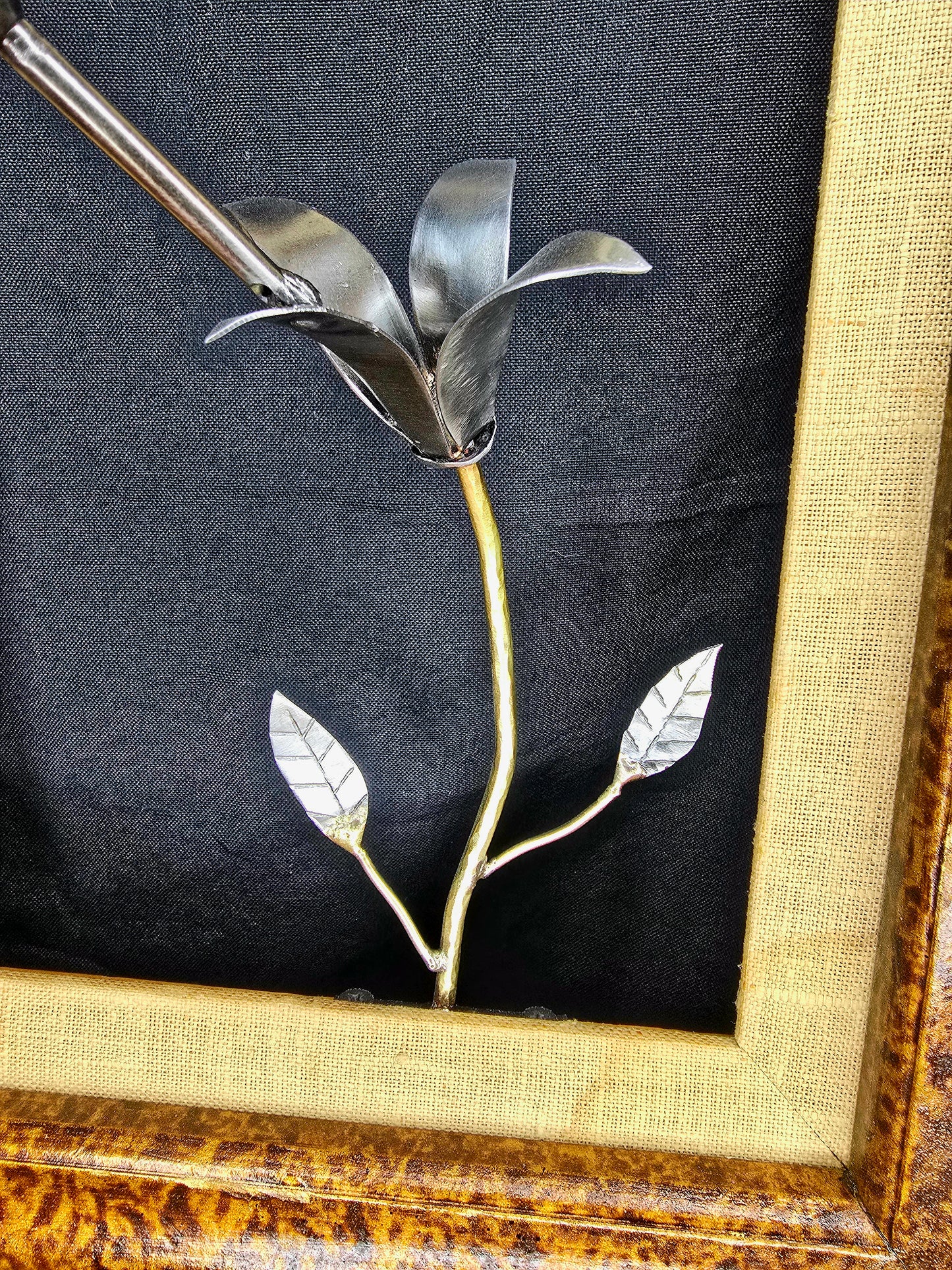 Framed metal bird sculpture with copper body, silver wings, and flower stems
