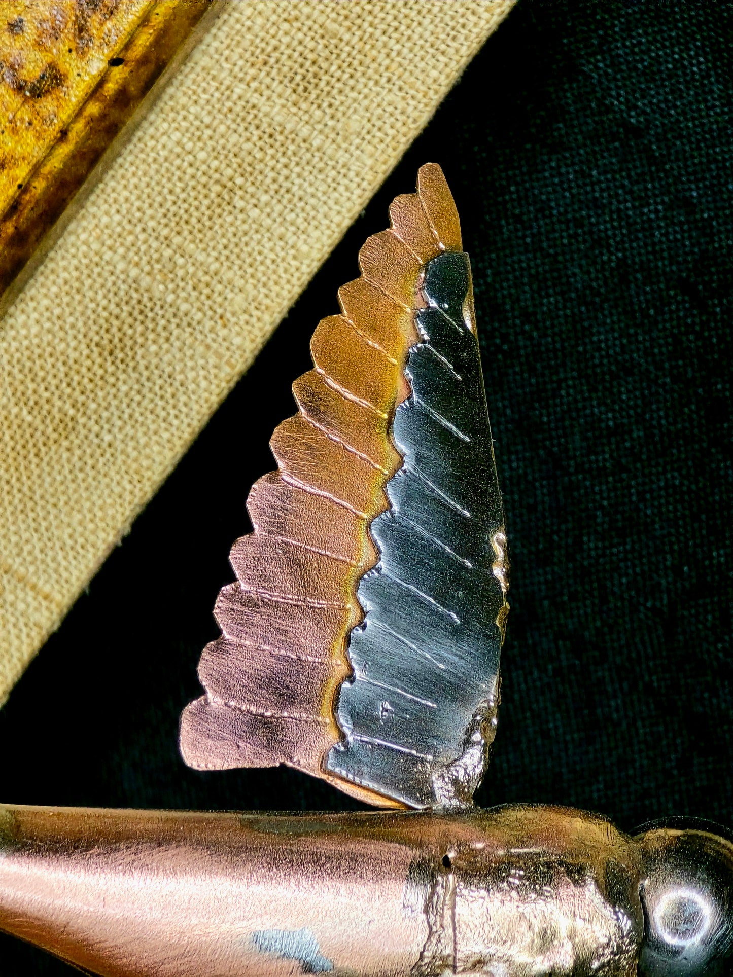 Metal flower petal detail with green center, mounted on a framed wooden backing