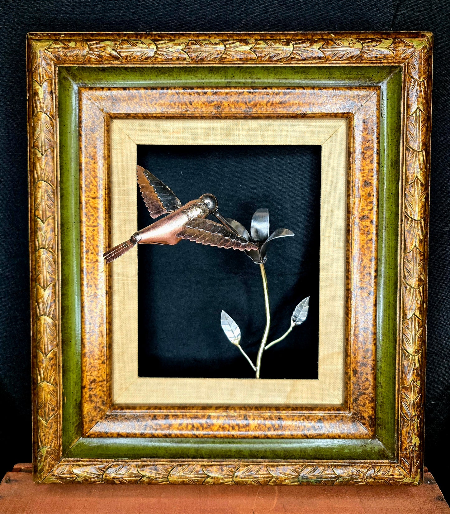 Framed metal bird sculpture with copper body and silver wings in a decorative frame