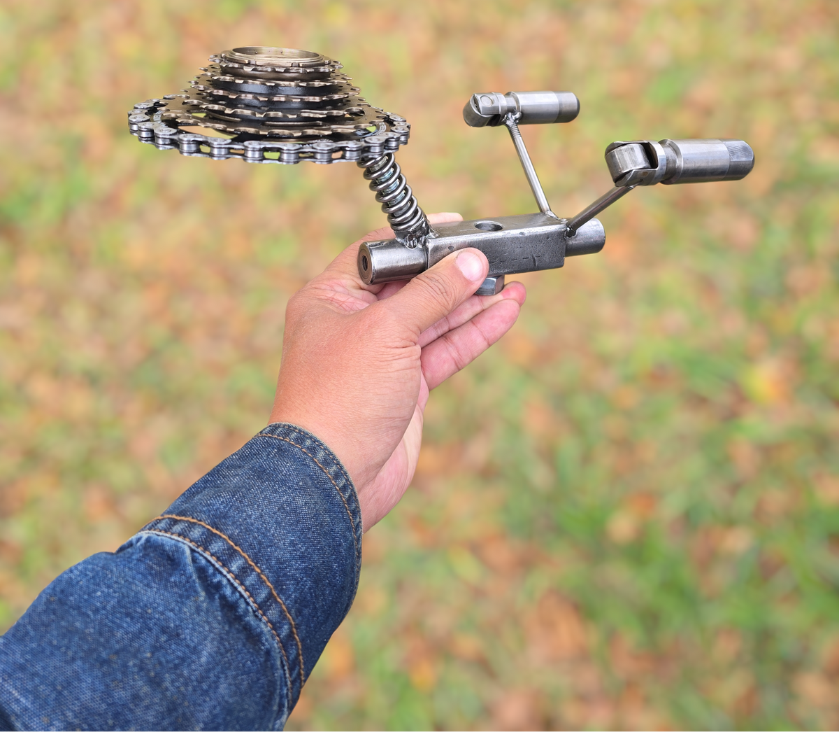 Hand holding a metal USS Enterprise sculpture by Enrique Del Angel, made from bicycle gears and metal parts.