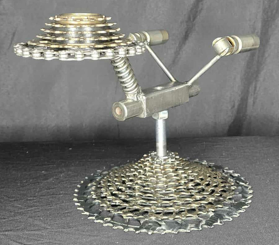 To Boldly Go Where No Man Has Gone Before sculpture by Enrique Del Angel, made of bicycle gears and metal parts, resembling the USS Enterprise.