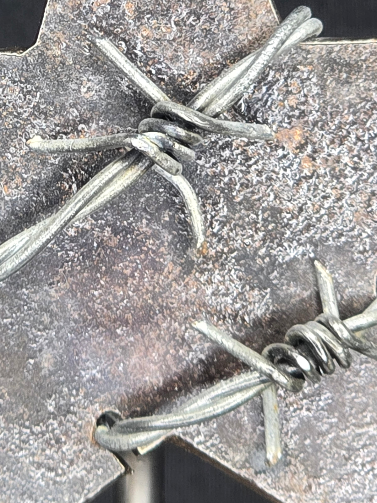 Where the Brass Falls, the Lone Star Rises sculpture by Enrique Del Angel. Steel Lone Star wrapped in barbed wire on a base with brass shell casings.
