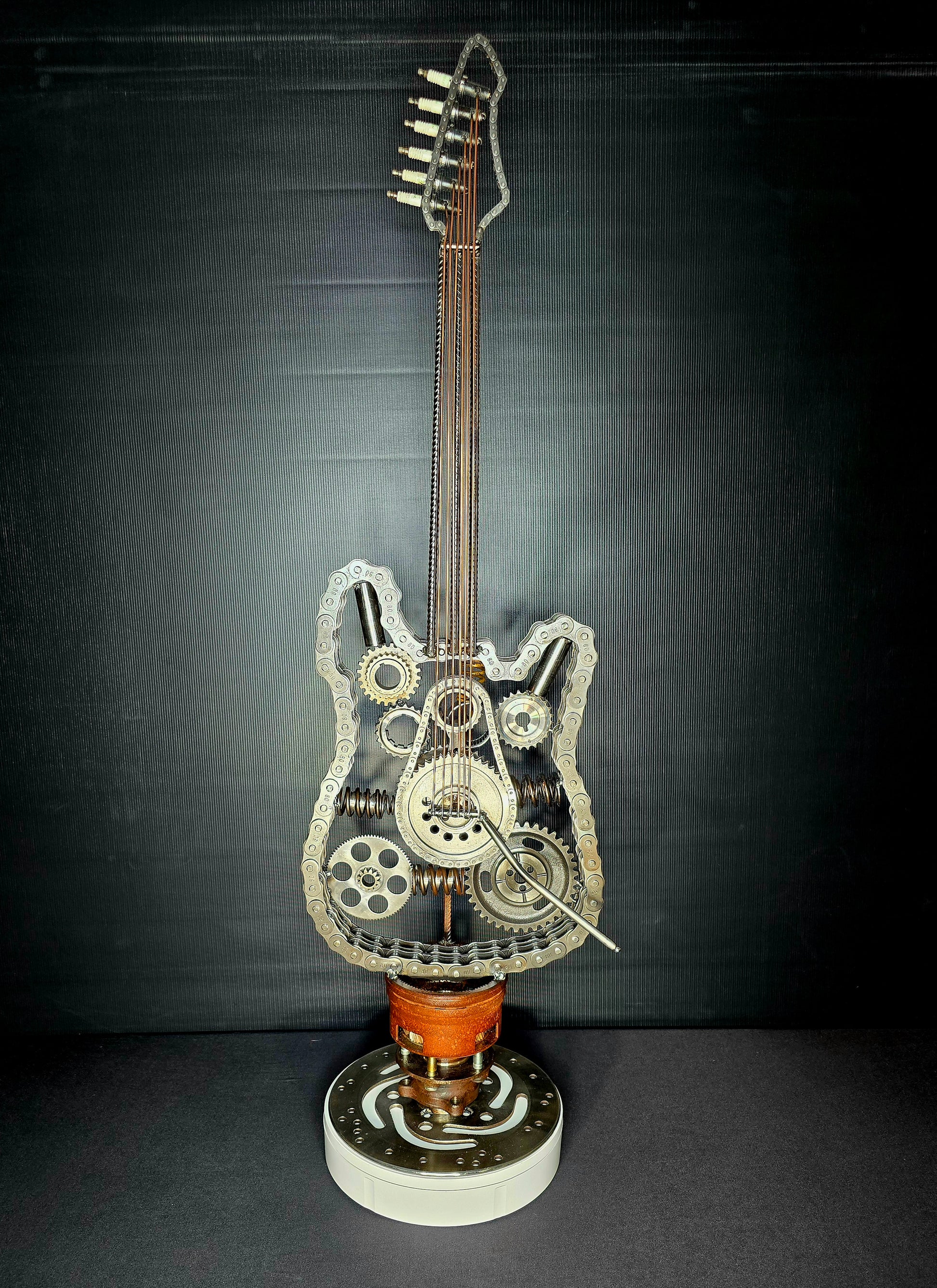Wired to Rock kinetic metal guitar sculpture by Enrique Del Angel, handcrafted from recycled chains, gears, springs, and engine parts. This interactive 4D sculpture features rotating components that add movement to the industrial guitar design.